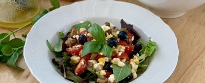 Fresh salad greens topped with grilled corn, tomatoes, basil and blueberries.